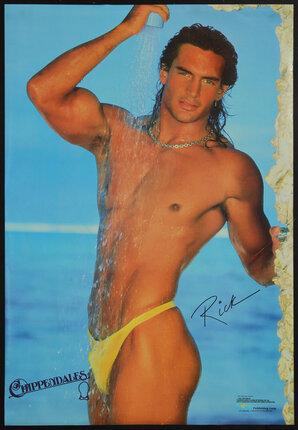 Bare-chested man in a speedo at the beach in a shower stream of water.