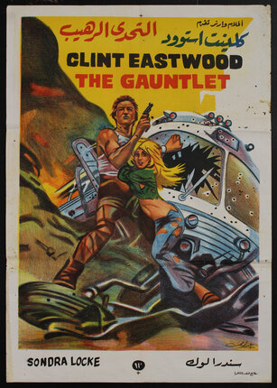 a movie poster of a woman clutching onto a man who is holding a gun and a crashed and bullet-riddled bus is behind them